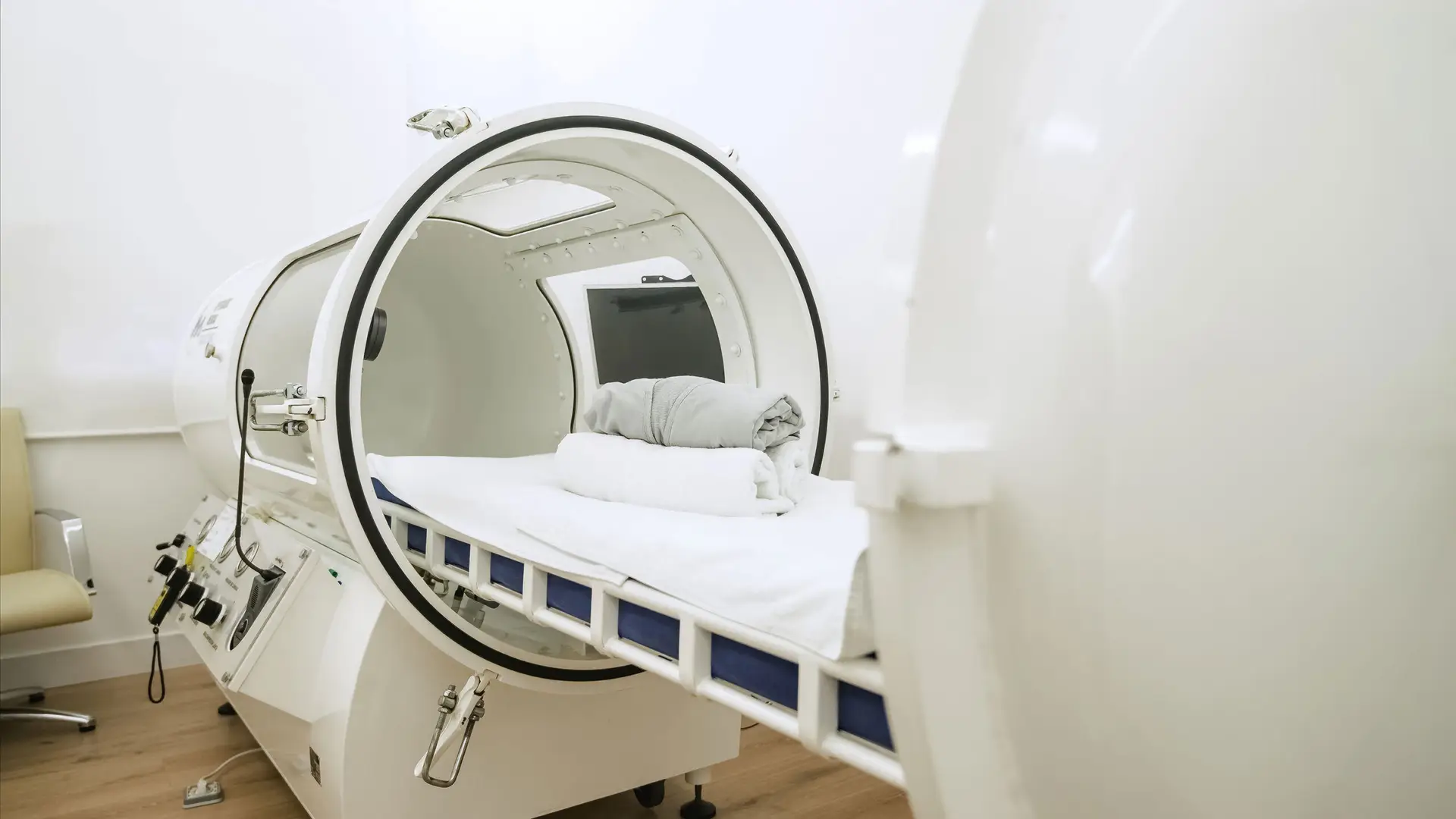 MRI scanner in a clinical radiology room with a patient bed and folded towels ready for imaging